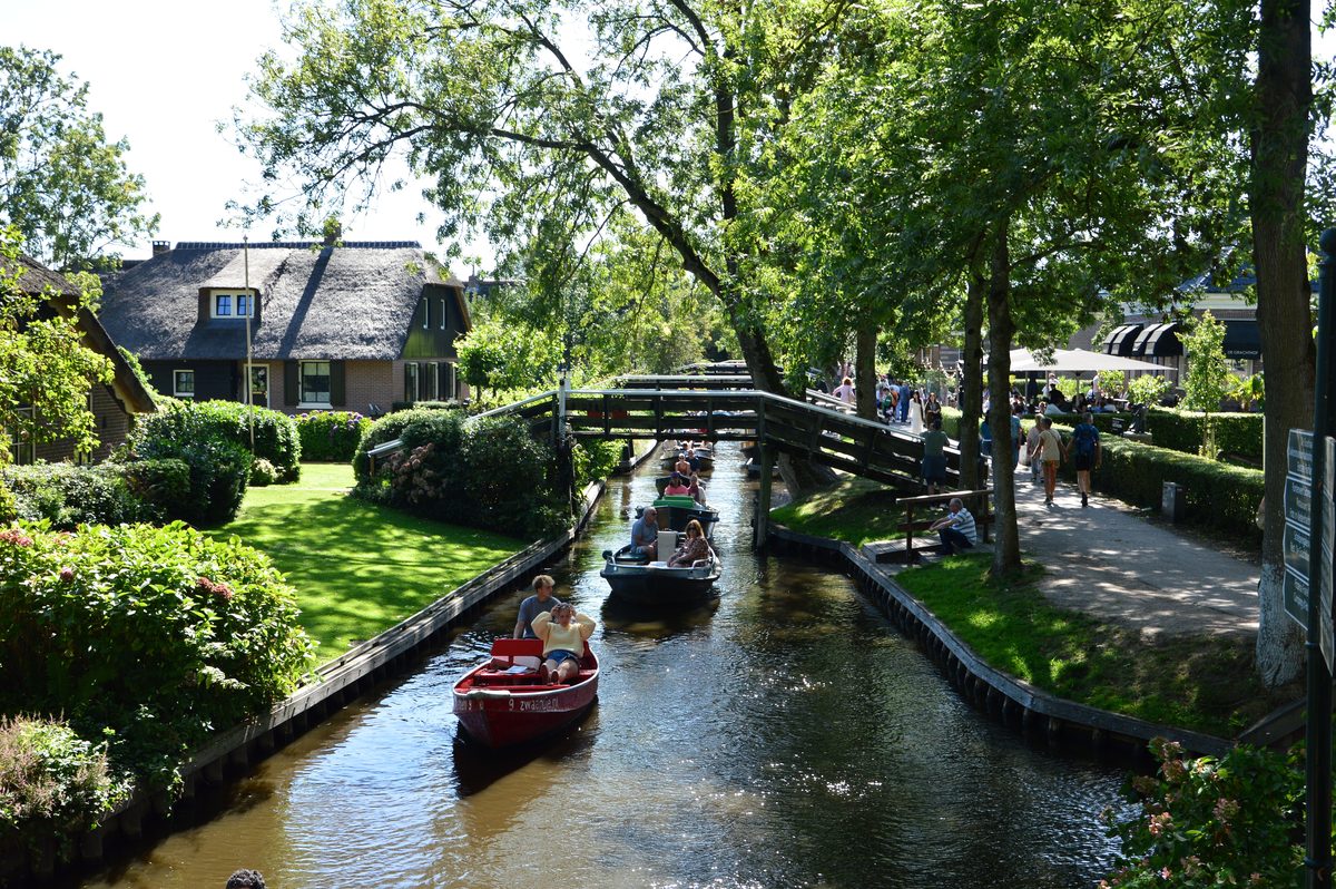 Bootjes op het grachtje van Giethoorn tussen rietgedekte huizen en groen